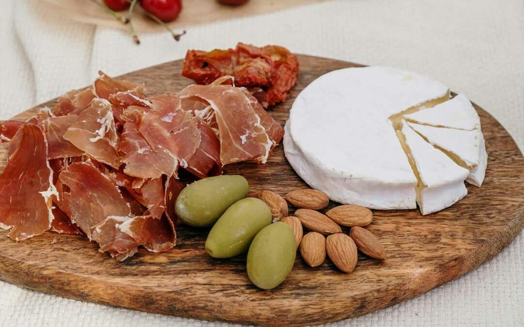 Un camembert de Normandie traditionnel présenté sur une planche en bois, accompagné de quelques tranches de pain rustique.